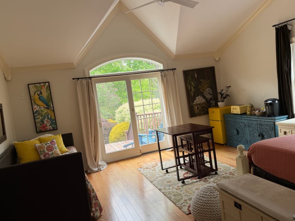 Bright studio suite with dining table, retro kitchenette, and hardwood floors